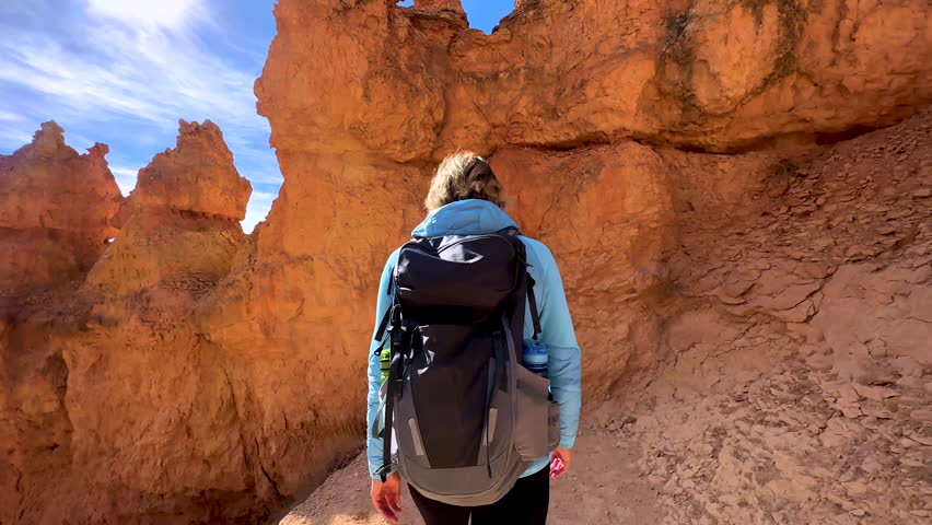 Motion tracking shot of female hiker walking in extreme outdoor adventure freedom Bryce Canyon Utah USA travel tourism