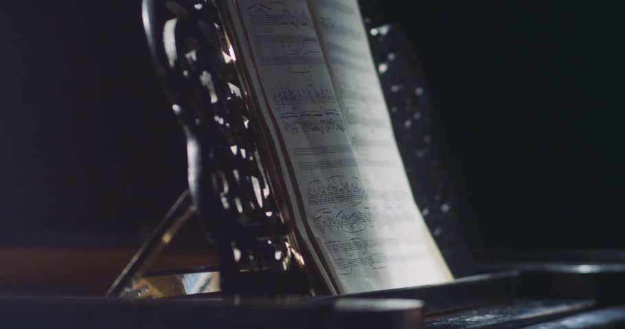 Closeup of hands holding a pencil above an elegant sheet of music, capturing creativity and artistry