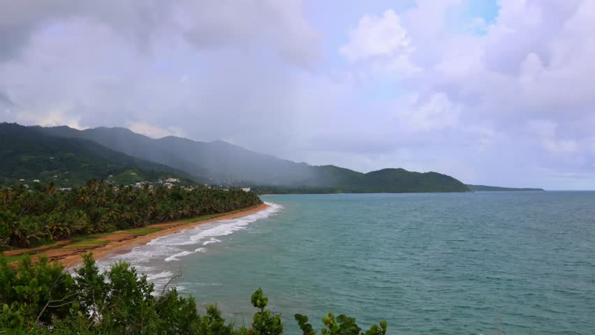 A timelapse view of green beach and mountain landscape in Loiza, Puerto Rico, with blue sea and cloudy sky