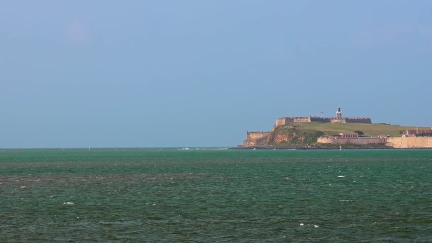 A view from the sea, showing El Morro Bay with a big cruise ship and Castillo San Felipe del Morro, on a sunny day in San Juan, Puerto Rico