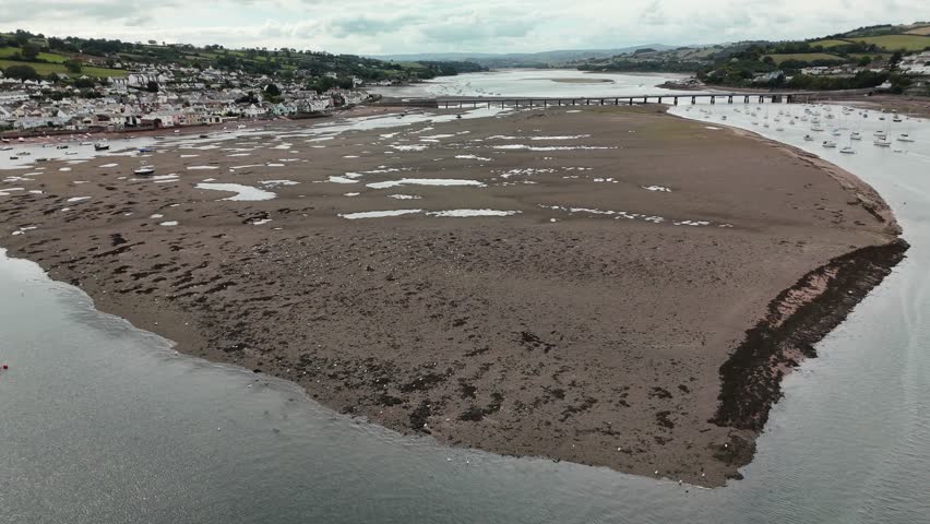 A drone flying over the water, reveals the Bridge connecting Shaldon to Teignmouth and the coastal houses in Devon, UK