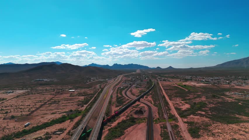 A drone view of roads and railway track in vast desert landscape, with blue sky background on a sunny day in El Paso, Texas