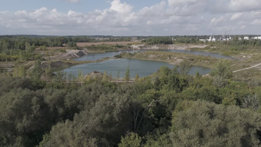 A drone view of the Grand River Trail surrounded by trees, ponds and vast fields on a sunny day with cloudy sky in Ontario, Canada