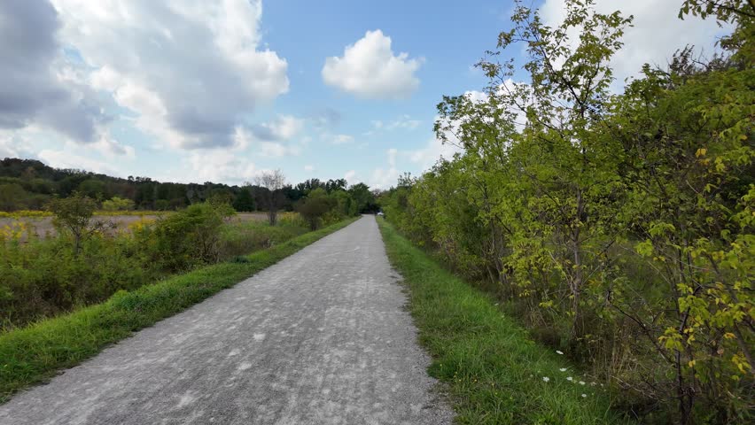 A footage of the Grand River Trail surrounded by lush greenery, under blue bright sky with white clouds in Ontario, Canada