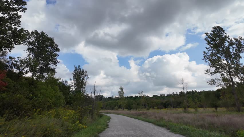 A footage of the Grand River Trail surrounded by lush greenery, under blue bright sky with white clouds in Ontario, Canada