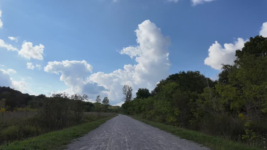 A timelapse of the Grand River Trail surrounded by lush greenery, under blue sky with white clouds in Ontario, Canada