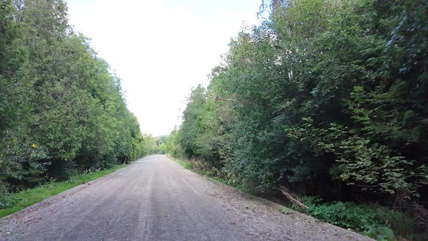 A footage of the Grand River Trail surrounded by lush trees, under blue sky with white clouds in Ontario, Canada