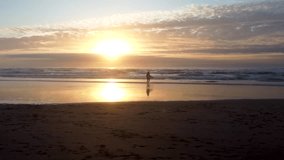 A surfer walking towards the waves of Atlantic Ocean at sunset time in Algarve, Portugal - Powered by Shutterstock - Get 15% off with code: PIKWIZARD15