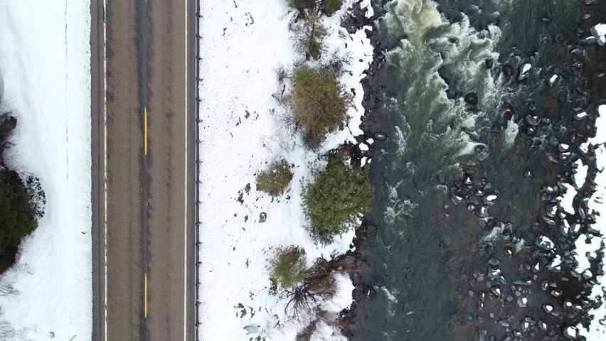 view looking down of a road next to a river in snowy winter conditions