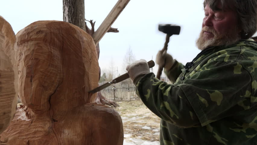 Wood Sculptor Engaging in the Carving of an Elaborate and Detailed Figure Amidst a Natural Setting. Stock Clip