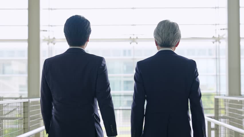 Back view of two business people walking through the lobby