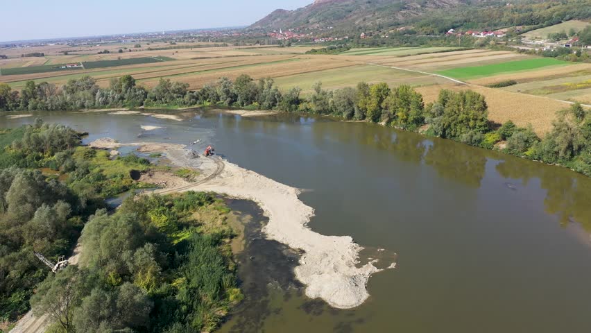 Aerial view of illegal exploitation of river sand and gravel with excavator on river bank by drone