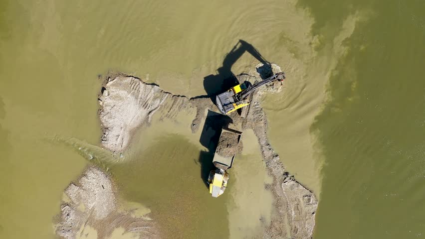 Aerial view of illegal exploitation of river sand and gravel with excavator on river bank by drone