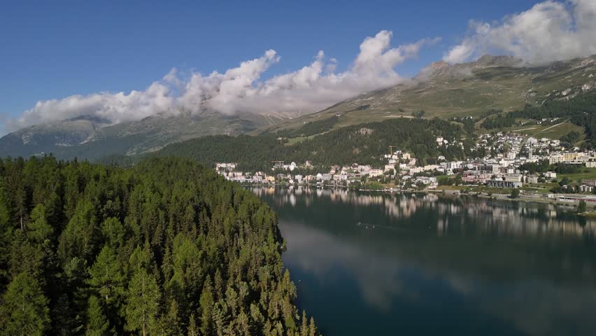 Aerial view of Lake St. Moritzersee in Graubünden, Switzerland, with majestic mountains towering above the residential houses, blending natural beauty with alpine living in a serene setting.