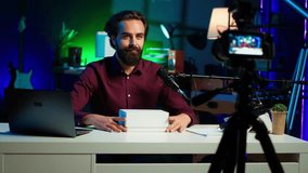 Tech guru using professional camera to film technology review of new cellphone, doing unboxing video. Content creator showing phone box to subscribers, recording with high tech gear, camera A - Powered by Shutterstock - Get 15% off with code: PIKWIZARD15