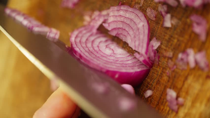 Vertical shot of a woman cutting an red onion into small pieces. High quality 4k footage