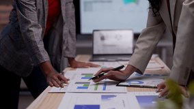 Two businesswomen collaborating in a meeting room, analyzing graphs and charts on a table. Concluding their discussion with a firm handshake - Powered by Shutterstock - Get 15% off with code: PIKWIZARD15