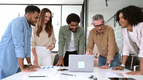 Diverse group of professionals leans in towards a laptop, sharing a moment of collaboration and interaction in their modern workspace. The energy and engagement of a diverse team working on a project - Powered by Shutterstock - Get 15% off with code: PIKWIZARD15