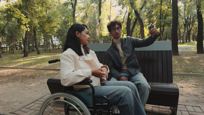 Young couple relaxing on bench taking selfies