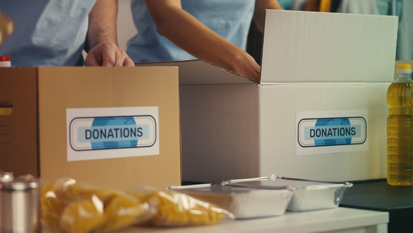 Team of charity center workers collecting donated food into boxes, volunteering