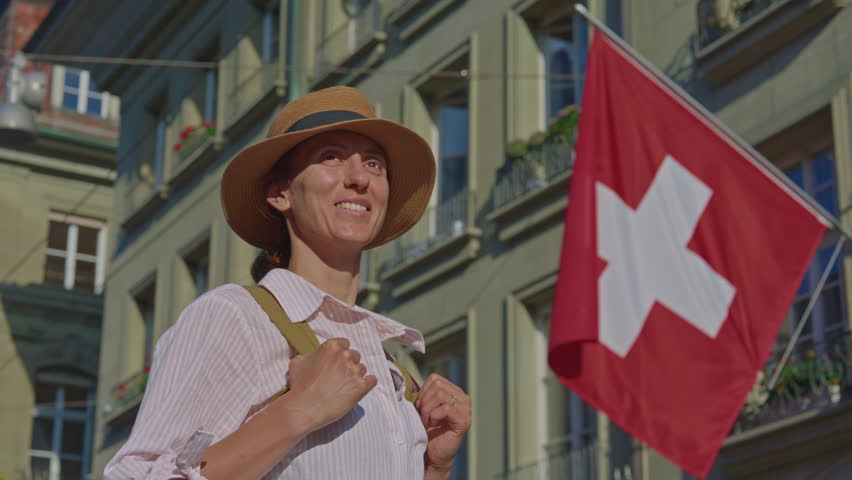 An attractive girl in a fashionable hat spends her holidays alone, traveling through the Alpine meadows. Tourist with a backpack travels through Switzerland with incredible views