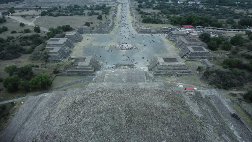 Aerial view of the Pyramid of the Sun and the Avenue of the Dead in Teotihuacan, Mexico. Tourists explore the ancient site, capturing the vast historical architecture from above.
