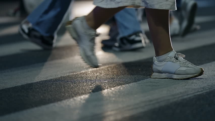 Slow motion people crowd various feet shoes steps busy city street. Many pedestrians walking crowded crosswalk. Evening rush hour legs asphalt zebra crossing, urban life, dark night, car headlights