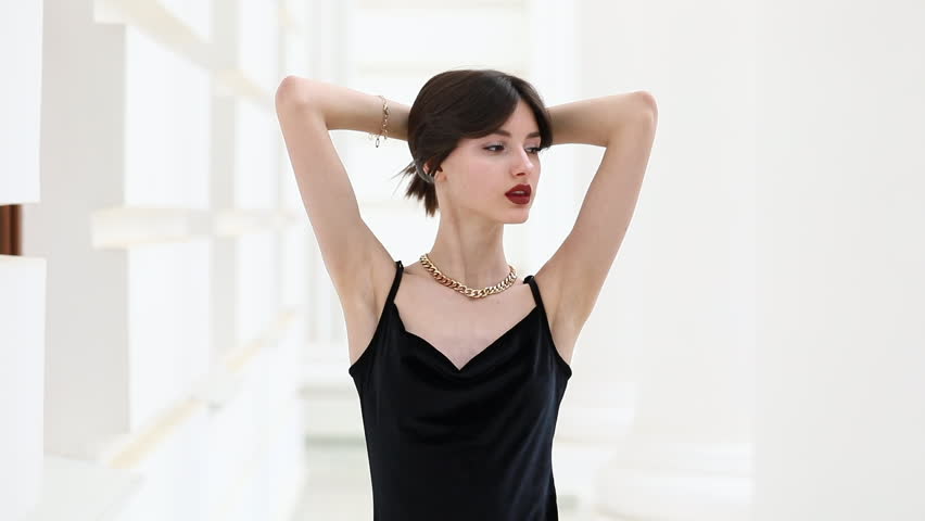 Young beautiful brunette girl posing in white columned hall