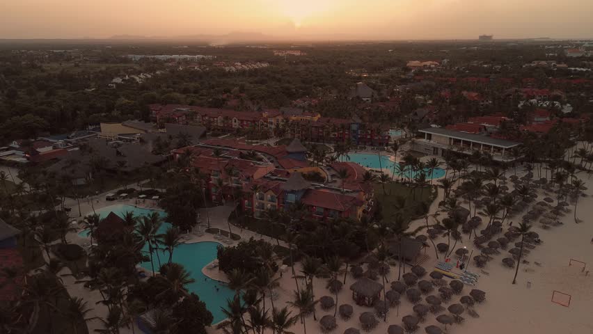 Aerial flight above luxury resort with swimming pool the public Bavaro beach with white sand. Turquoise water of the Caribbean sea and tourist boats. Punta Cana, Dominican republic