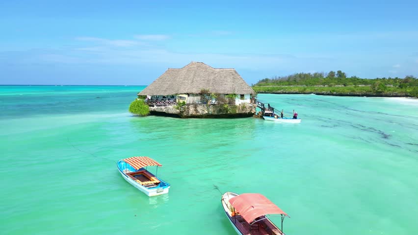 Drone Aerial view Zanzibar, Africa. Tourists guests arrive to restaurant on rock in sea. Tropical island vacation. Tanzania tourism destination. 
