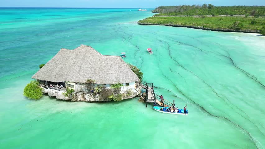 Drone Aerial view Zanzibar, Africa. Tourists guests arrive to restaurant on rock in sea. Tropical island vacation. Tanzania tourism destination. 
