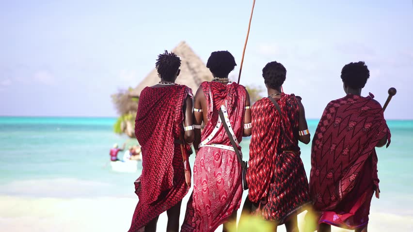 Africa Maasai men in traditional outfit on beach, rock restaurant in sea. African warrior tribesman in Zanzibar tropical island. tourism destination in Tanzania. 