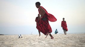 Maasai men in traditional outfit, young men friends play beach soccer. Football in Africa,  Zanzibar tropical island in Tanzania.    - Powered by Shutterstock - Get 15% off with code: PIKWIZARD15