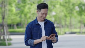 Happy Asian man is smiling  and using phone on the park city , street - Powered by Shutterstock - Get 15% off with code: PIKWIZARD15