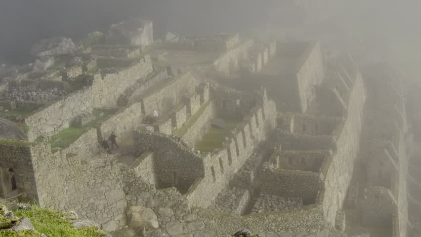 Machu Picchu lost city zoom out, with tourists walking. Cold foggy morning. Wide shot, panorama, scenic