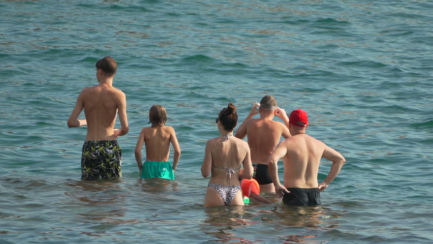 Beach People Water - Group of people standing in shallow water at the beach on a sunny day.