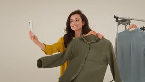 Carefree Caucasian blogger girl streamer smile speaking filming blog influencer use mobile phone in studio. Glad woman model compare clothes fashion recording video vlog on smartphone female streaming - Powered by Shutterstock - Get 15% off with code: PIKWIZARD15