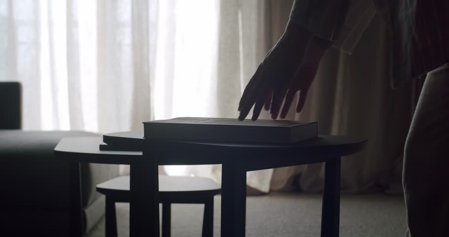Serene living room scene featuring a modern coffee table with a book, bathed in natural light through soft curtains. Perfect for depicting tranquility and relaxation in a contemporary home.