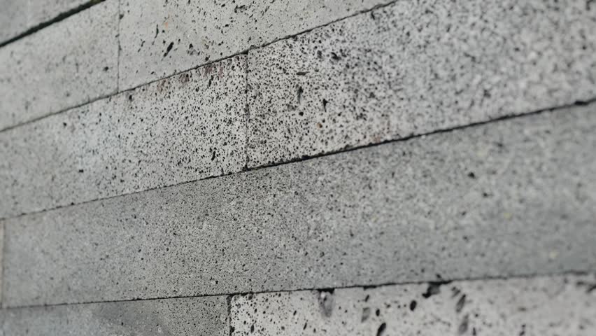 Close up photo of a gray concrete wall showcasing the rugged texture and intricate details of the material. Close-Up of Concrete Brick Wall Showing Texture and Pattern. Wall Texture and Details
