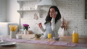 Happy smiling communicate speak Caucasian woman pregnant female girl mother smile talking mobile phone talk smartphone eating healthy fresh tasty salad food meal vegetables diet kitchen pregnancy - Powered by Shutterstock - Get 15% off with code: PIKWIZARD15