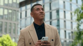 Confident smiling happy positive African American ethnic businessman man business guy male investor employer entrepreneur in city chatting texting browsing mobile phone using smartphone in downtown - Powered by Shutterstock - Get 15% off with code: PIKWIZARD15