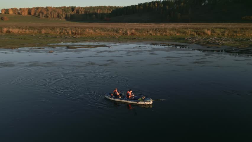 Two men are rafting on a calm river on an inflatable kayak and fishing on the Siberian river in autumn. The concept of active weekend in the wild.