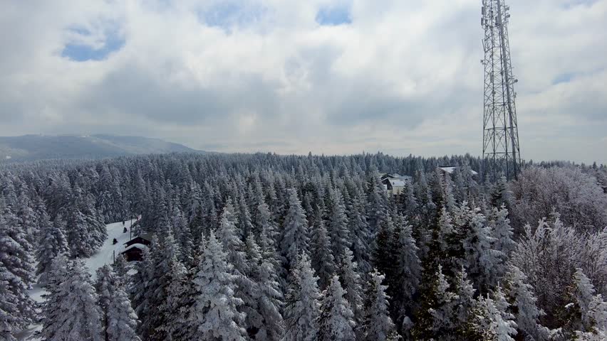 Uludağ mountain aerial view in a snowy day. the trees are covered with white snow with blue cloudy sky. pan view from above the mount uludag, road with cars on the hills of Bursa city, Turkey Türkiye