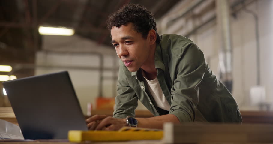 Carpentry, workshop and man with laptop checking email, inventory or creative project at small business. Warehouse, wood work and carpenter with online website for furniture, design or manufacturing
