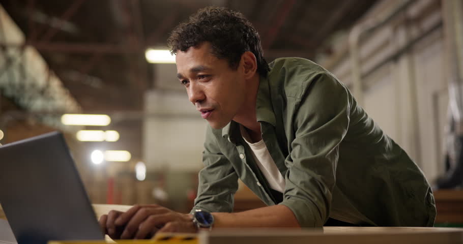 Carpentry, workshop and man with laptop checking email, inventory or creative project at small business. Warehouse, wood work and carpenter with online website for furniture, design or manufacturing