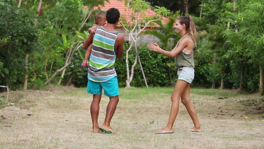 Parents play with their daughter on yard