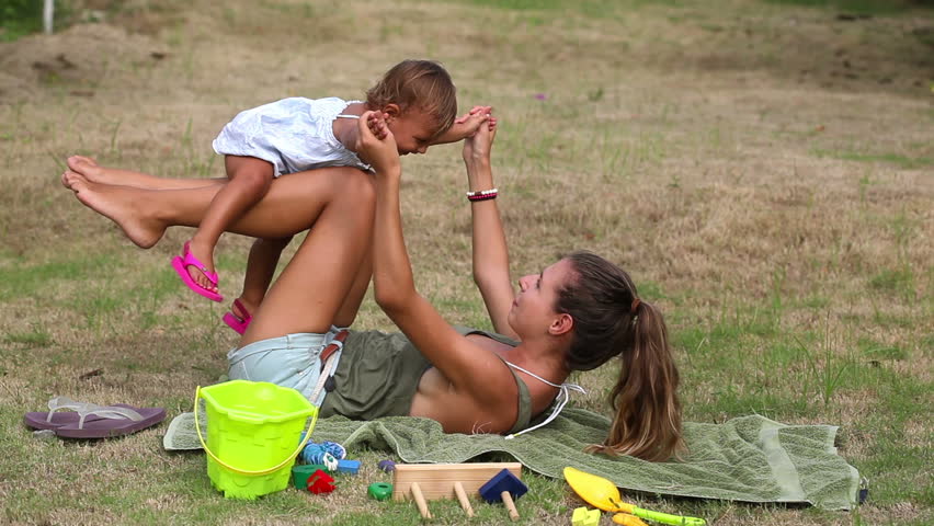 Beautiful mother raises girl on her legs have fun
