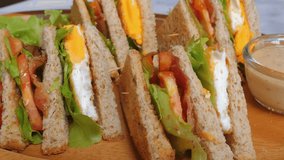Close-up of freshly made club sandwiches with layers of egg, tomato, lettuce, and cheese served on whole grain bread with side of dipping sauce. Healthy Eating and Food Preparation. - Powered by Shutterstock - Get 15% off with code: PIKWIZARD15