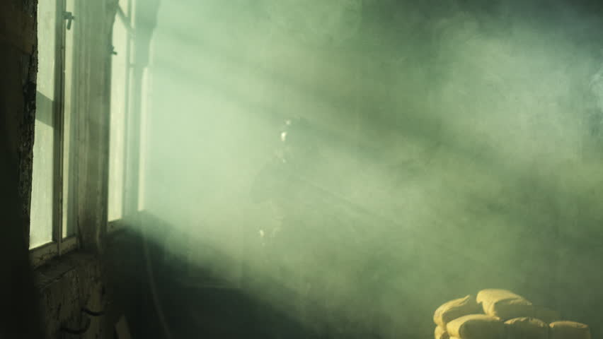 Special forces operator in black military gear and an m4 assault rifle in a room full of smoke