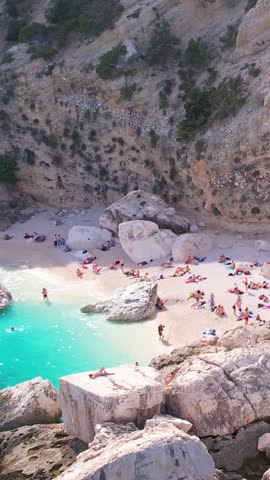 Aerial drone view on white sand Cala Baunei in Orosei Gulf of Sardegna. Warm turquoise sea and small beach surrounded with green mountains on the Sardinia island.